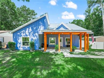 Charming blue home featuring a spacious porch with wooden beams and a well-manicured front lawn at 7714 Chase Rd, Lakeland, FL 33810