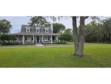 Charming home with lush green lawn, mature trees, and welcoming front porch at 1976 Holy Cow Rd, Polk City, FL 33868