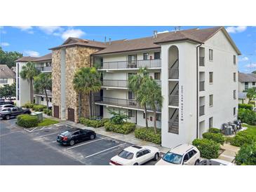 Exterior view of condo building with stone accents, balconies, well maintained landscaping and ample parking at 2037 San Marcos Se Dr # 443, Winter Haven, FL 33880