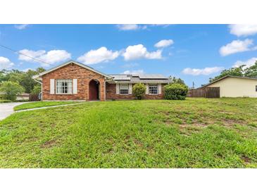 Charming brick home features a well-manicured lawn, crisp white shutters, and solar panels at 326 Sunset Rd, Frostproof, FL 33843
