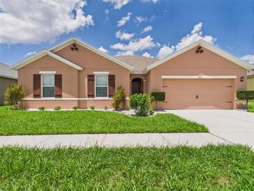 Single-story home featuring a well-manicured lawn, neutral color scheme, and attached two-car garage at 5751 Lakeside Landings Blvd, Winter Haven, FL 33881