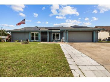 Charming single-story home featuring a lush lawn, solar panels, and an inviting walkway at 704 Butternut Pl, Lakeland, FL 33813