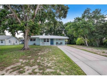 Charming single-story home with a well-maintained lawn, covered front porch, and a long, concrete driveway at 124 Tyler St, Lake Wales, FL 33859