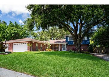 Charming brick home featuring a lush green lawn and mature trees offering plenty of shade at 237 Manatee Rd, Winter Haven, FL 33884
