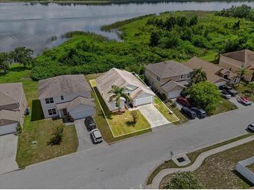 An aerial view of a single-Gathering home near a lake with a well-manicured lawn and mature landscaping at 2740 Rochelle Dr, Winter Haven, FL 33881