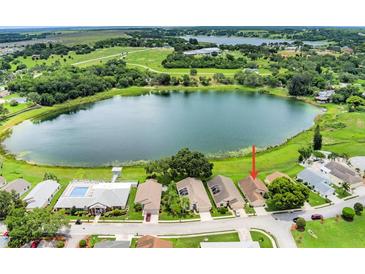 An aerial view shows the house with lake access, a nearby pool, and mature landscaping at 464 Lake Suzanne Dr, Lake Wales, FL 33859