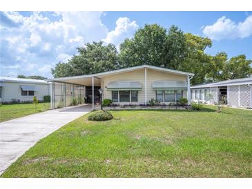 Inviting single-story home featuring a well-maintained lawn, covered carport and manicured landscaping at 6027 Grand Oaks Se Dr, Winter Haven, FL 33884