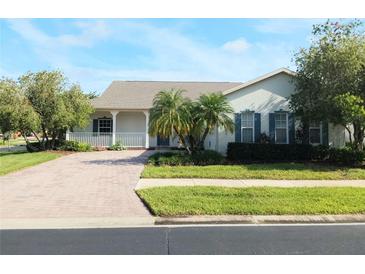 Charming home featuring a welcoming front porch, brick driveway, and lush landscaping at 130 Prima Dr, Kissimmee, FL 34759