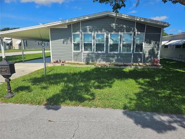 Charming single-story home with light gray siding, a covered parking area, and a well-maintained front lawn at 6685 Briarhill Dr Ne, Winter Haven, FL 33881