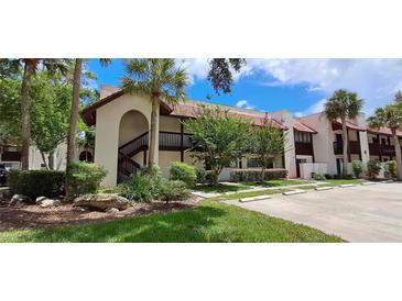 Condominium building featuring lush landscaping, a red tile roof, and a private stairwell at 7201 Country Club Dr # G21, Lake Wales, FL 33898