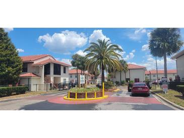 Inviting community entrance featuring lush landscaping and well-maintained buildings with eye-catching red tile roofing at 6294 River Run Pl # 193, Orlando, FL 32807