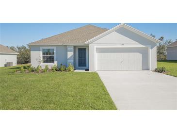 Charming single-story home featuring a two-car garage, blue front door, and neatly manicured lawn at 2173 Emma Ln, Lake Wales, FL 33859