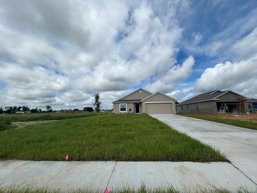 Newly constructed one-story home with attached garage and grassy yard at 322 Brennan Ave, Frostproof, FL 33843