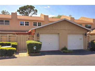 Townhouse exterior with two-car garage, neutral stucco, tidy landscaping, and brick-paved driveway at 1019 Grove St # 85, Maitland, FL 32751