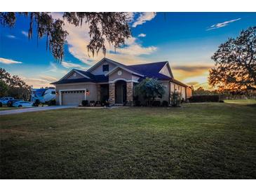 Charming single-Gathering home with a well-manicured lawn and attached two-car garage under a picturesque sunset at 1004 Country Oaks Ln, Lakeland, FL 33810