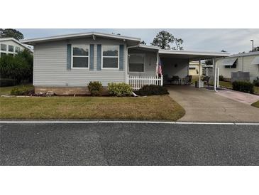 Single-wide manufactured home with covered carport and small front yard at 110 Dogwood Trl, Leesburg, FL 34748