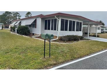 Mobile home with carport, mature landscaping, and mailbox at 188 Azalea Trl, Leesburg, FL 34748