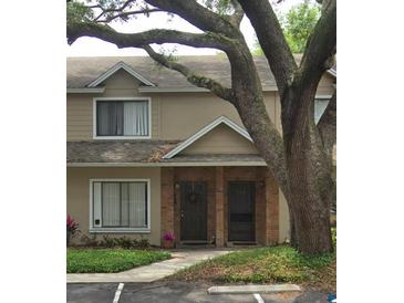 Two-story tan townhouse with a brick facade and a mature tree in the front yard, offering curb appeal at 255 Sandlewood Trl # 4, Winter Park, FL 32789