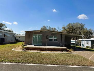 Charming single-story home featuring a covered porch and carport with a well-maintained lawn at 100 Papaya Cv, Leesburg, FL 34748