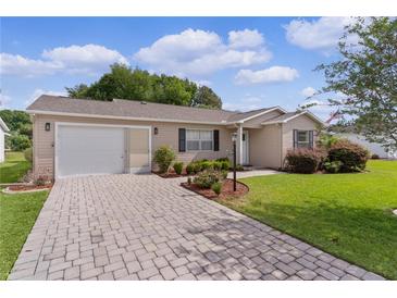 Charming home featuring a brick driveway, attached garage, and well-maintained landscaping at 1411 Juarez Pl, The Villages, FL 32159