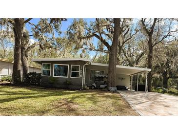 Charming single story home featuring mature landscaping and a convenient covered parking area at 106 Royal Palm Dr, Leesburg, FL 34748