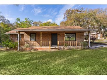 Charming single-story home featuring a cozy front porch, wood siding, and a well-manicured lawn at 1107 Linmar Ave, Fruitland Park, FL 34731