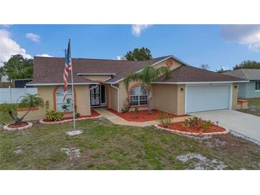 Charming single-story home featuring a well-manicured lawn, American flag, and attached two-car garage at 1134 Norwood Dr, Deltona, FL 32725