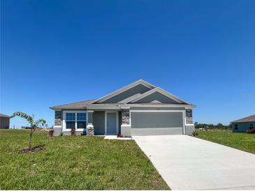 Charming single-story home featuring a gray exterior, stone accents, and a well-manicured lawn at 1212 Caloosa Ridge Ave, Babson Park, FL 33827