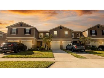 Charming townhomes with attached garages, well-manicured lawns and driveways on a sunny afternoon at 1412 Mirabella Cir, Davenport, FL 33897