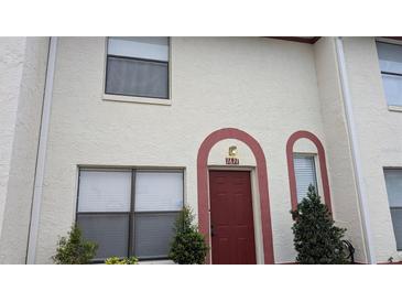 Two-story condo featuring a red door and a light-colored stucco exterior at 1617 Shady Ridge Ct # 257, Orlando, FL 32807