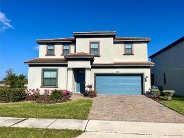 Charming two-story home with a blue garage door, brick driveway, and manicured lawn at 207 Aidans Lndg, Haines City, FL 33844