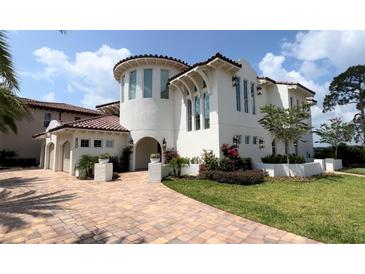Elegant two-story home featuring a stucco exterior, tiled roof, arched entryway, and lush landscaping at 800 Stephens Pass Cv, Lake Mary, FL 32746