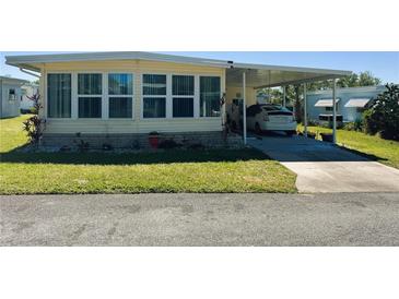 Charming mobile home with large windows and attached carport in a well-maintained community at 114 Caladium St, Leesburg, FL 34748