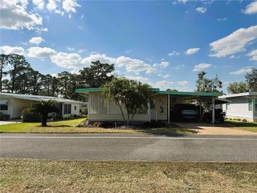 Charming home with covered parking, palm trees, and landscaped front yard at 334 Palo Verde Dr, Leesburg, FL 34748