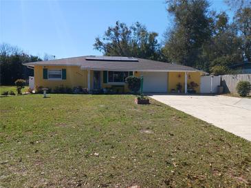 Charming ranch-style home featuring a well-maintained lawn, solar panels, and a quaint garden bed in front at 6832 Oswego Dr, Mount Dora, FL 32757