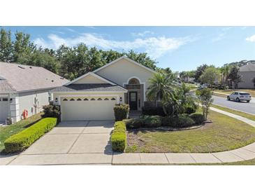 Charming single-story home with a well-manicured lawn, mature trees and a two-car garage at 9324 Pecky Cypress Way, Orlando, FL 32836