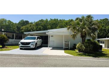 Charming single-story home with a well-manicured lawn, carport, and landscaped with a palm tree at 106 Palo Verde Dr, Leesburg, FL 34748