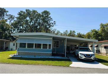Charming single-story home featuring a carport, well-maintained lawn, and light blue siding at 121 Bougainvillea Dr, Leesburg, FL 34748