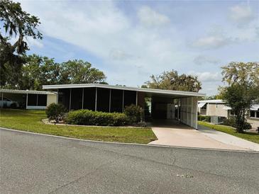 Charming single-story home with a carport, screened porch, and nicely landscaped front yard at 139 Royal Palm Dr, Leesburg, FL 34748