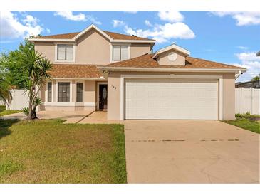 Two-story home featuring an attached garage, well-manicured lawn, and a classic architectural design at 144 Pinewood Cir, Kissimmee, FL 34743