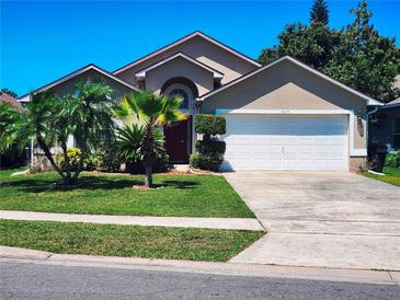 Inviting single-Gathering home showcasing a well-manicured lawn and driveway leading to an attached two-car garage at 4613 Eaglet Ln, Kissimmee, FL 34746