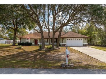 Charming one-story home with mature trees, a well-manicured lawn, and a two-car garage at 10441 Sw 54Th Ct, Ocala, FL 34476