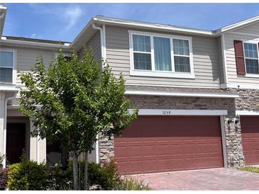 Exterior view of home featuring a two-car garage with brick paver driveway at 1258 Wispy Cypress Drive Dr, Kissimmee, FL 34746