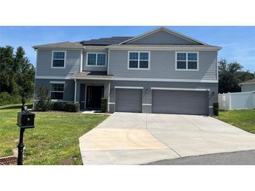 Beautiful two-story home featuring a two-car garage, grey siding, and solar panels on the roof at 1940 Bell Creek Loop, Fruitland Park, FL 34731