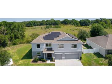 Two-story home with a three-car garage, manicured lawn, and solar panels at 1940 Bell Creek Loop, Fruitland Park, FL 34731