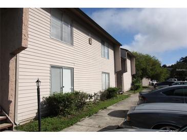Two story condo building with light beige siding and well manicured landscaping at 2117 Lyme Bay Dr # 604, Orlando, FL 32839