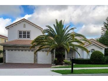 Charming two-story home featuring a three car garage, tile roof, and a tropical palm tree in the front yard at 2408 Dahlgren Way, Winter Garden, FL 34787