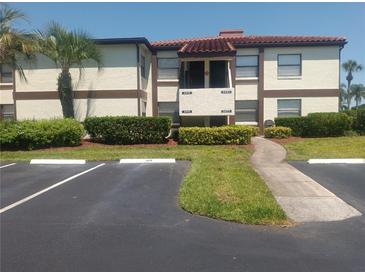 Well-maintained two-story condo building with landscaping, palm trees, and visible parking area at 3475 Flossmoor Ave # 103, Orlando, FL 32822