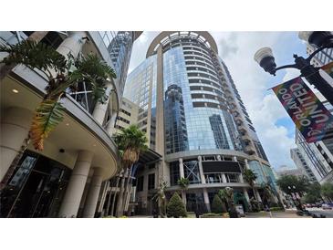 Contemporary building featuring expansive glass windows, street level statues, and lush palm trees at 155 S Court Ave # 1801, Orlando, FL 32801