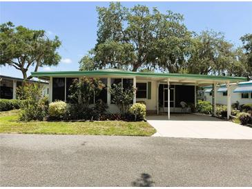 Charming single-story home featuring a covered carport, screened porch, and well-maintained landscaping at 201 Jacaranda Dr, Leesburg, FL 34748